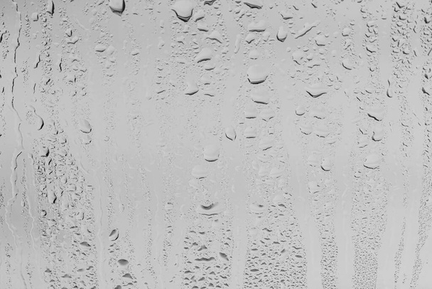 Sade putoaa ikkunalasien pinnalle harmaalla taivastaustalla. Sadepisaroiden luonnollinen tausta. Abstrakti päällys suunnitteluun. Käsite huono sateinen sää. - Valokuva, kuva