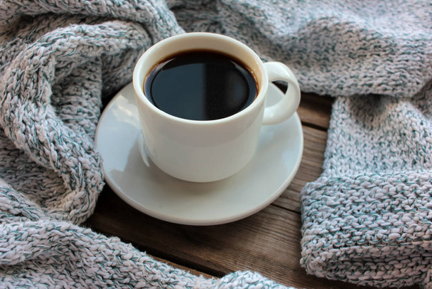 Κύπελλο καφέ και ανοιχτό γκρι πλεκτό πουλόβερ σε ρουστίκ ξύλινο φόντο. Άνετο φθινόπωρο ή χειμώνα έννοια. Πάνω όψη, αντιγραφή χώρου - Φωτογραφία, εικόνα