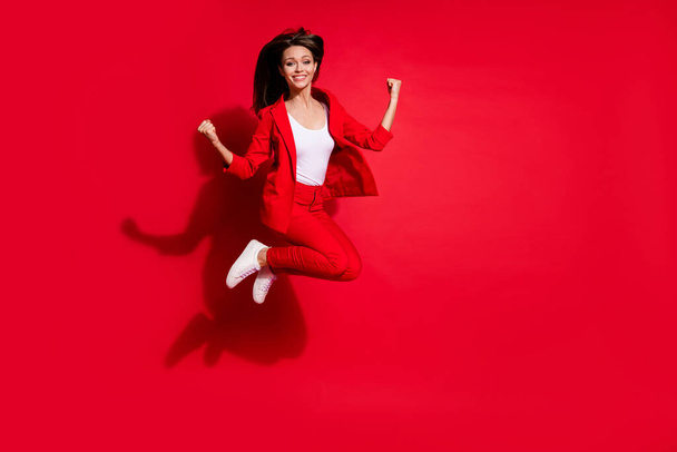Full length photo of attractive lady worker having fun jumping high up good mood celebrate startup success wear blazer suit pants footwear isolated bright red color background - Zdjęcie, obraz
