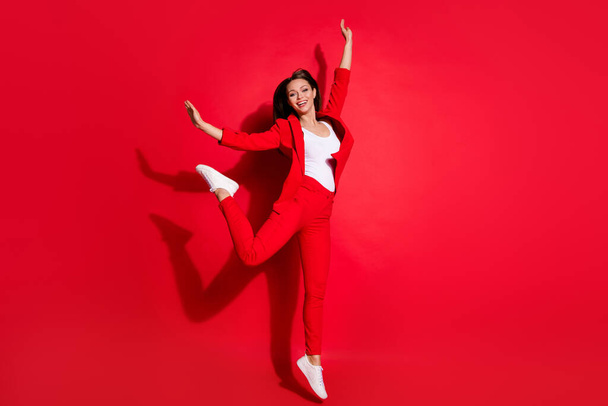 Full length photo of attractive funny lady successful worker having fun jumping high up good mood rejoicing wear blazer suit pants footwear isolated bright red color background - Foto, immagini