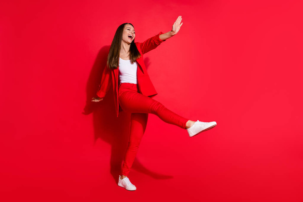 Full length profile photo of attractive funny business lady success worker walk home street vacation having fun wear office blazer suit pants white shoes isolated bright red color background - Φωτογραφία, εικόνα