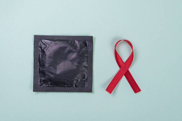 Red ribbon and latex condom on the green background - Foto, afbeelding