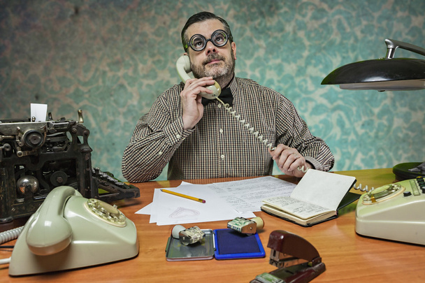Työntekijä, jolla on silmälasit, puhuu puhelimessa toimistossa
 - Valokuva, kuva