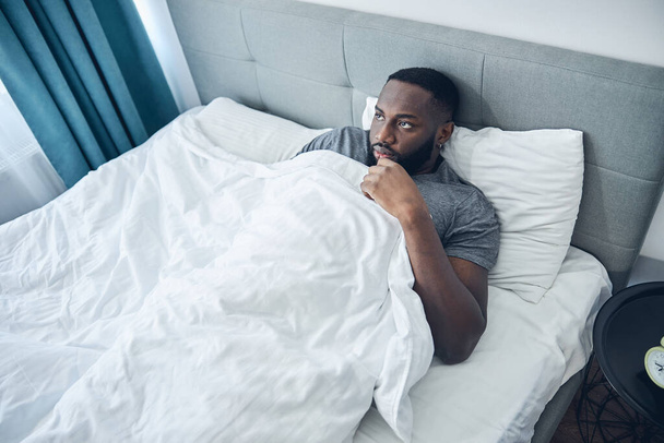 Unatkozó nemzetközi férfi személy fekszik az ágyában - Fotó, kép