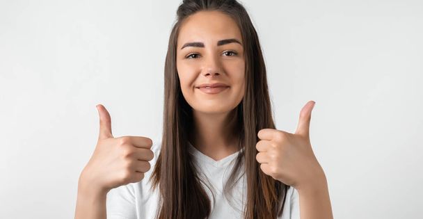 Good job. Pretty carefree modern stylish European girl with long chestnut hair making OK with both hands, gesture as if saying that everything is finee, white background - Photo, Image