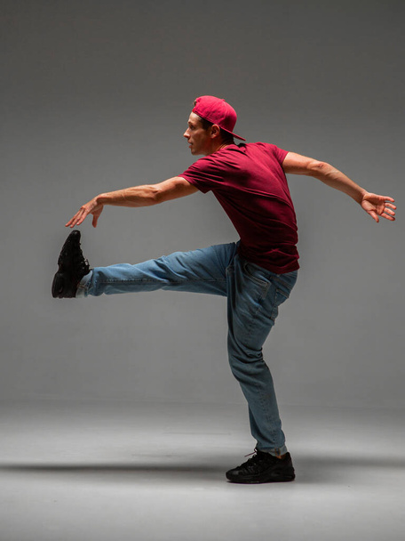 Guy dancing contemporary dance in studio. Neon light blue background. Acrobatic bboy dancer. Break dance lessons. - Foto, Imagen