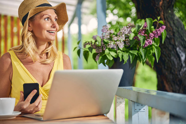Happy woman with a gadget sitting outside - Zdjęcie, obraz