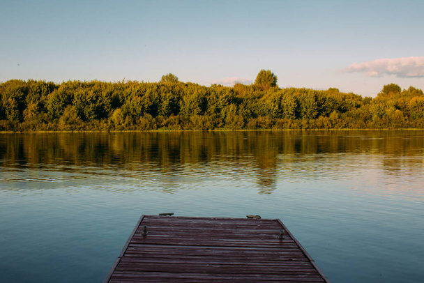 Wooden pier without people on tranquil lake or river. Summertime landscape photography - Фото, зображення