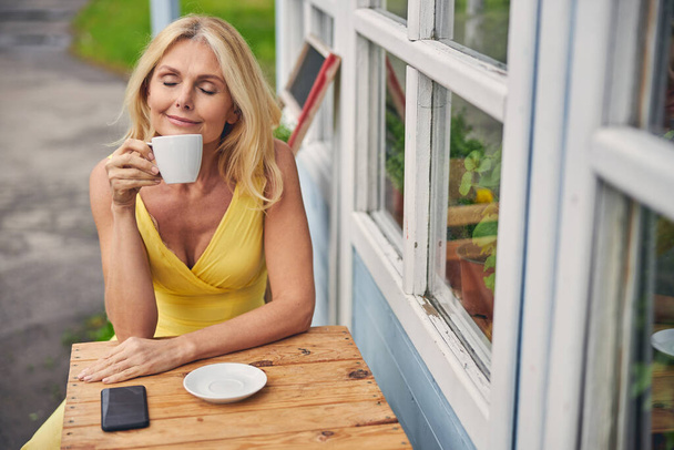 Γαλήνια ξανθιά Καυκάσια κυρία πίνει καφέ έξω - Φωτογραφία, εικόνα