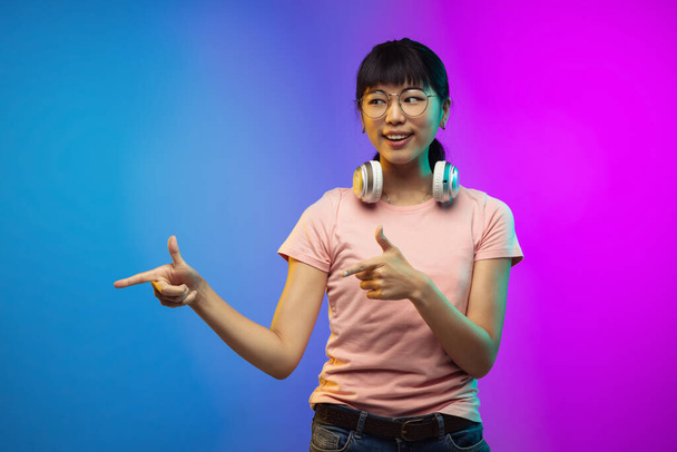 Asian young womans portrait on gradient studio background in neon - Foto, afbeelding
