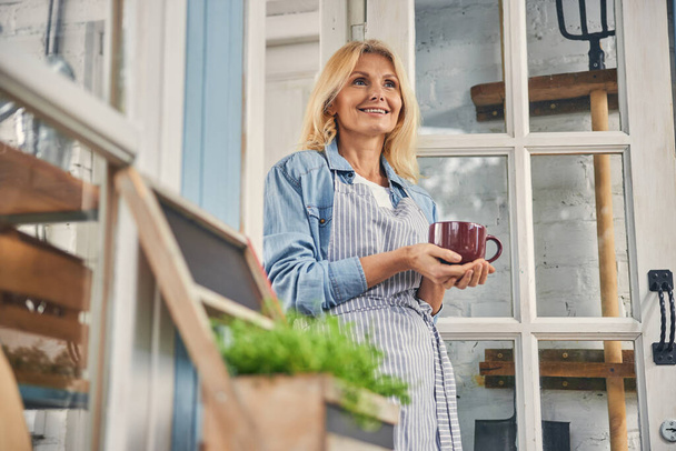 Cheerful woman holding a mug with both hands - Photo, Image