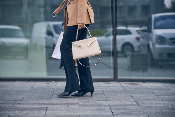Νεαρή γυναίκα με μοντέρνο παντελόνι που περπατάει σε εξωτερικούς χώρους - Φωτογραφία, εικόνα
