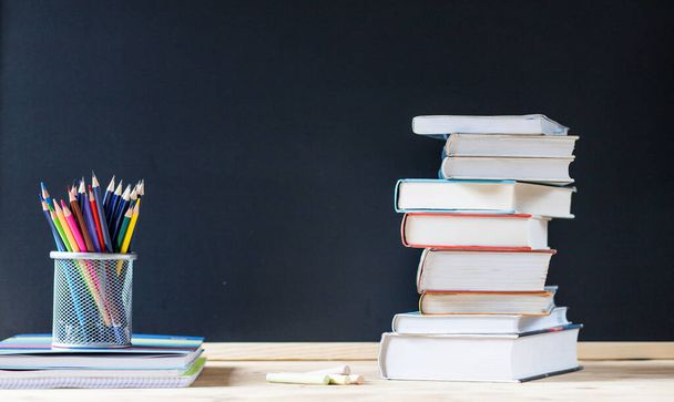 back to school concept pile of books against chalkboard - Foto, imagen