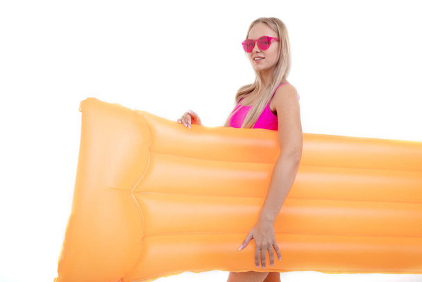 A beautiful blonde girl in a pink swimsuit and glasses holds an air mattres - Фото, зображення