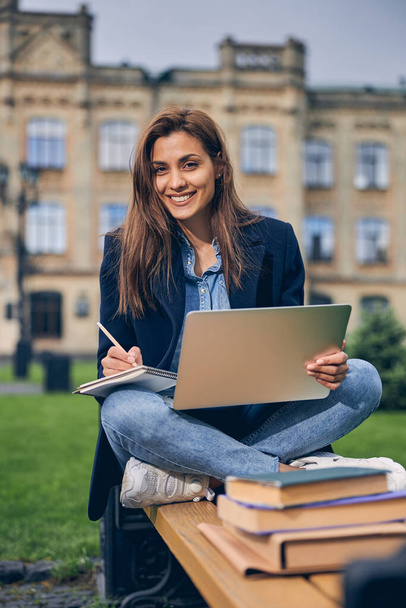 Ελκυστική νεαρή γυναίκα απολαμβάνει να σπουδάζει μόνη της έξω - Φωτογραφία, εικόνα