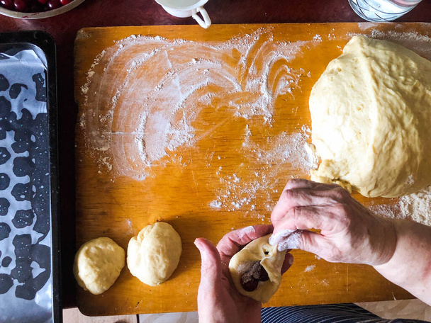 女性の手は、生地からチェリーとパイを彫刻.揚げパイの調理. - 写真・画像