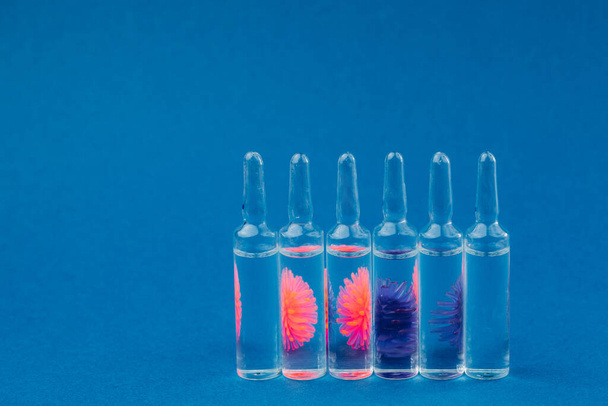 Abstraktní model koronaviru a ampulky s lékem na modrém pozadí.Koncepce ochrany proti pandemickému viru. - Fotografie, Obrázek