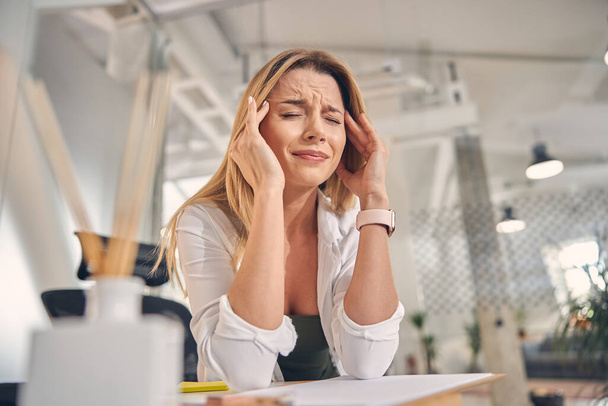 Mulher jovem sobrecarregada com dor de cabeça no trabalho - Foto, Imagem