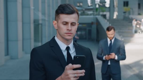 Handsome Businessman Using App on his Smartphone on Streets of Business District. Checking News, Mails. Looking Confident, Successful. Suit Dressed. - Footage, Video