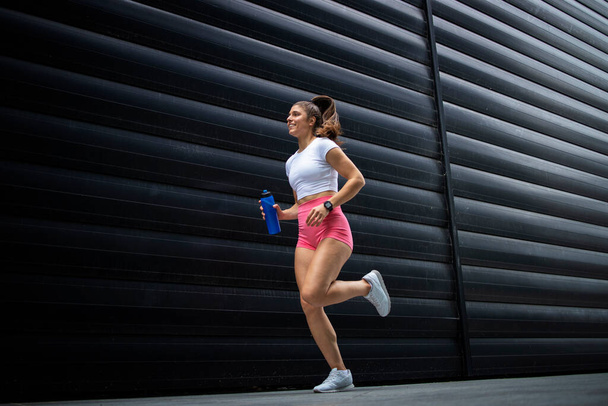 Female athlete running and jogging against black background. - Фото, зображення