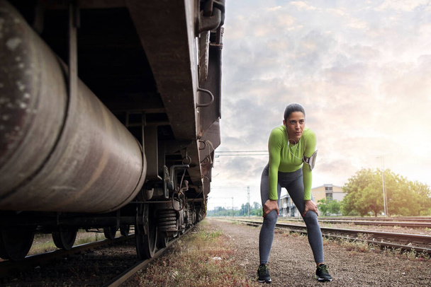 Sportos női futó áll a vonat jármű és egy kis szünetet futás után edzés. Sport és fitness. - Fotó, kép
