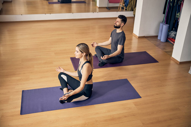 Blonde Frau und ein dunkelhaariger Mann beim Yoga - Foto, Bild