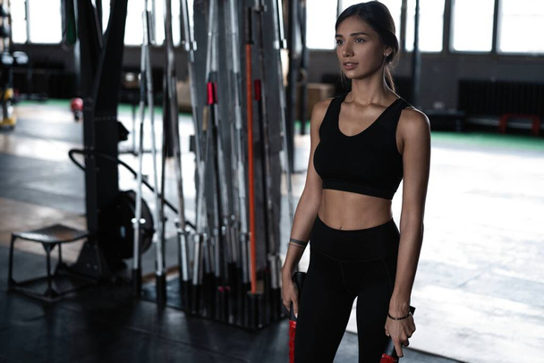 Shot of strong woman standing in crossfit gym and looking away. Confident fitness female model in sportswear. - Foto, Imagen