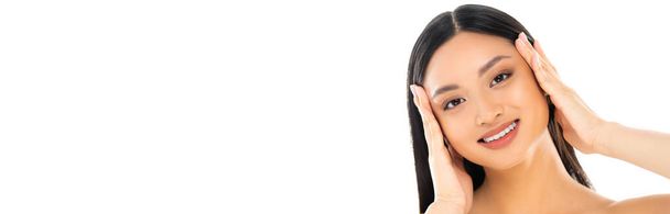 Panoramic shot of young asian woman touching face isolated on white - Foto, afbeelding