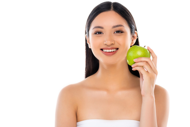 Emocionado joven asiático mujer mirando a cámara y sosteniendo manzana aislado en blanco - Foto, imagen