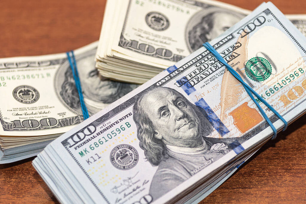 Sok száz dolláros bankjegyek fa asztal háttér textúra. Egy rakás pénz szétszórva az irodai asztalon. vagyon és jövedelem fogalma - Fotó, kép