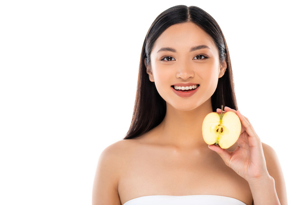 brunette asian woman looking at camera while holding half of ripe apple isolated on white - 写真・画像