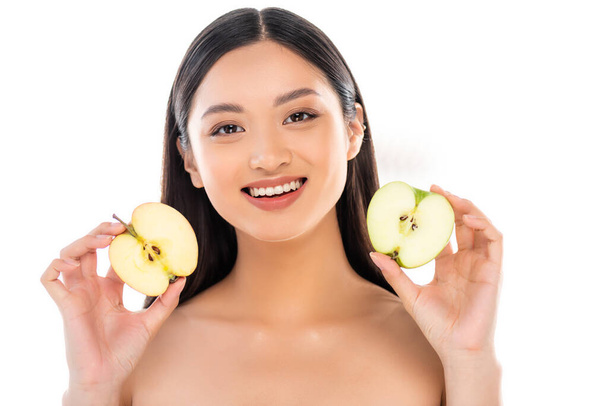 Çıplak Asyalı kadın kesilmiş elmayı tutarken beyaz kameraya bakıyor. - Fotoğraf, Görsel