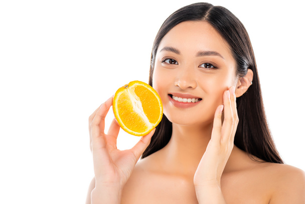 nackte asiatische Frau berühren Gesicht, während die Hälfte der saftigen Orange isoliert auf weiß - Foto, Bild