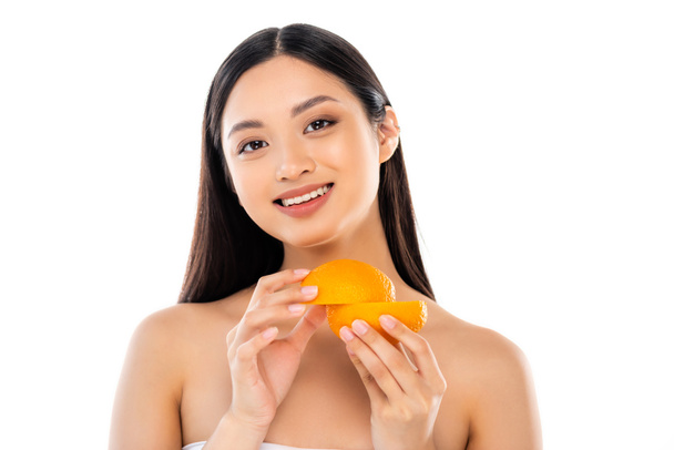 nackte asiatische Frau schaut in die Kamera, während sie ausgeschnittene Orange isoliert auf Weiß hält - Foto, Bild