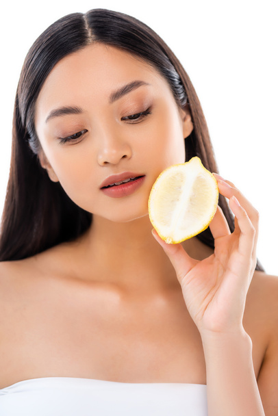 dromerige aziatische vrouw houden de helft van sappige citroen geïsoleerd op wit - Foto, afbeelding