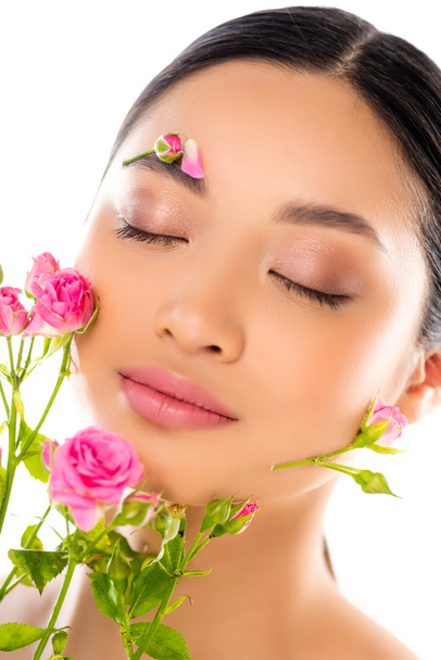 retrato de sensual asiático mulher com fechado olhos, flores no rosto, perto minúsculo rosas isolado no branco - Foto, Imagem