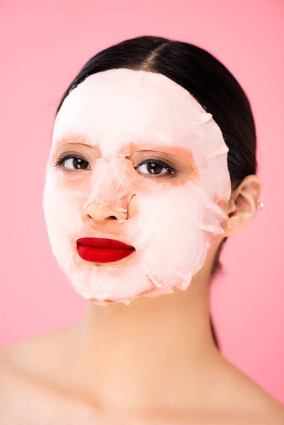 asian woman in face mask looking at camera isolated on pink - Fotografie, Obrázek