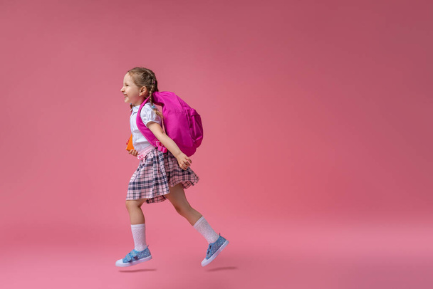Back to school! Cute hardworking kid in uniform Jogging on pink background. Child with backpack. little girl is ready for school. Dynamic images that go back to conceptual school. beginning holidays. - 写真・画像