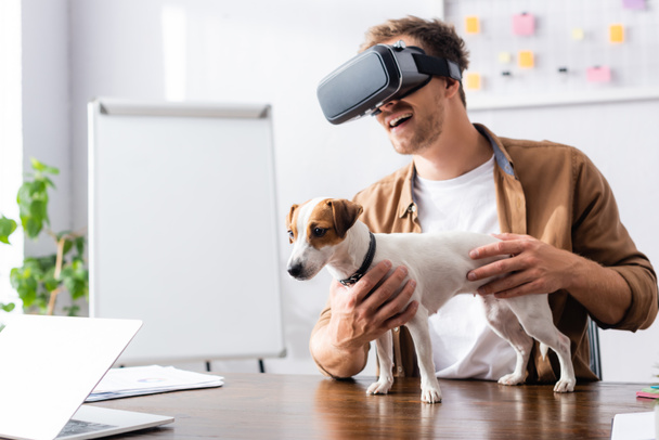 young businessman in vr headset with jack rassell terrier dog on office desk - Foto, imagen
