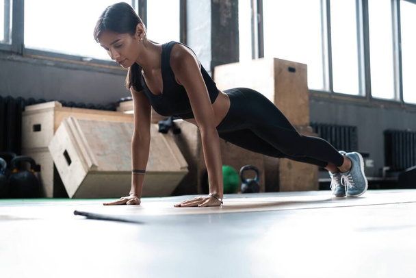 Woman doing planks on gym floor. Healthy lifestyle concept - 写真・画像