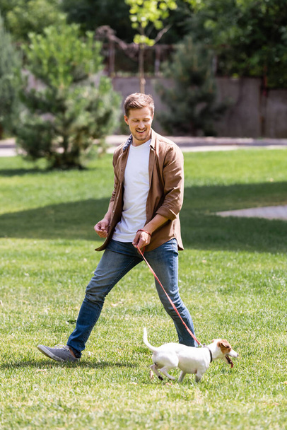 Selective focus of man looking at jack russell terrier on leash in park  - Foto, imagen