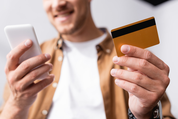 Cropped view of businessman holding credit card and using smartphone  - 写真・画像