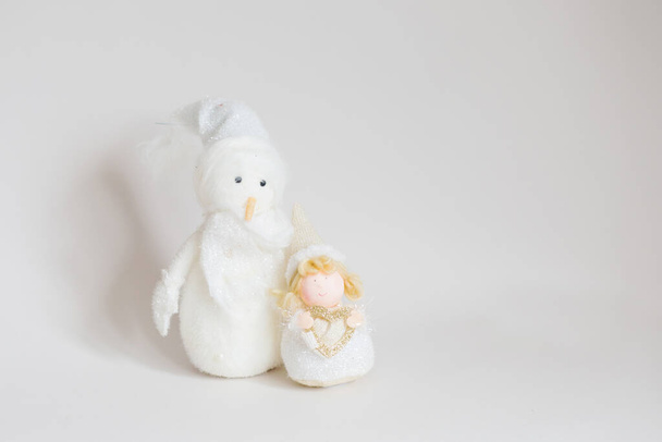 Sneeuwman speelgoed en kerst engel op licht grijze achtergrond  - Foto, afbeelding