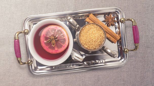 Top view op a tea service on a tray. Background or banner related to tea. Concept of breakfast, healthy and organic food. Metallic tray with cinnamon, anise, sugar and tea with orange. Copy space. - Photo, Image
