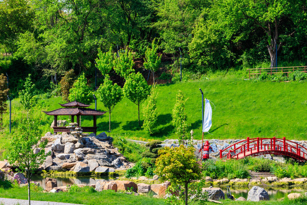 Червоний міст і ґебо біля ставка в японському саду. - Фото, зображення