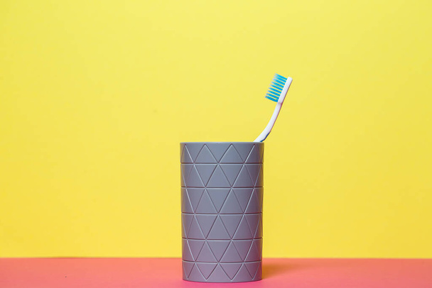 A blue toothbrush is standing in a gray glass. Dental care concept - Fotó, kép