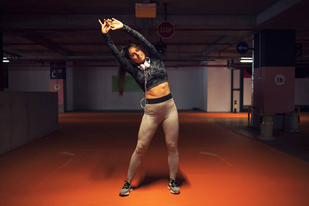 女性アスリートはトレーニング前に彼女の筋肉ボディを伸ばす。フィットネスとトレーニング. - 写真・画像