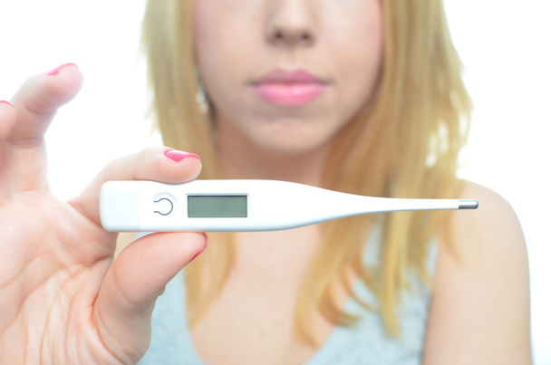 jonge vrouw nemen temperatuur en pillen - Foto, afbeelding
