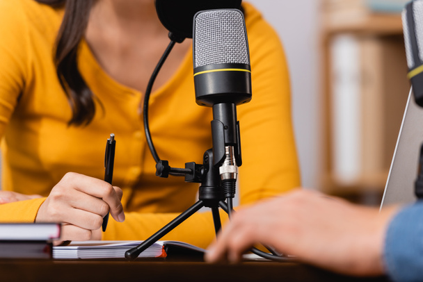 άποψη του ραδιοτηλεοπτικού φορέα που κρατά στυλό κατά τη διάρκεια συνέντευξης με τον άνθρωπο στο ραδιοφωνικό στούντιο - Φωτογραφία, εικόνα
