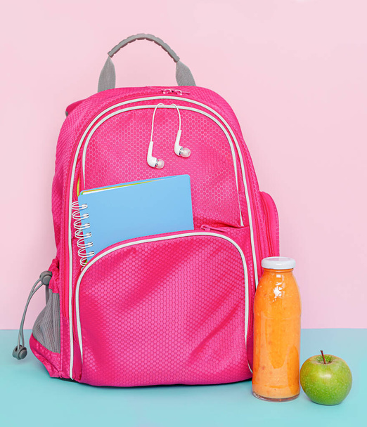 Pinkfarbener Rucksack mit Snack aus Frucht-Smoothie-Flasche und Apfel. Zurück zum Schulkonzept - Foto, Bild